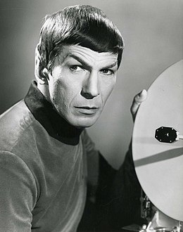 A black-and-white publicity portrait of Spock (actor Leonard Nimoy) in his Starfleet uniform, holding a round viewscreen panel.